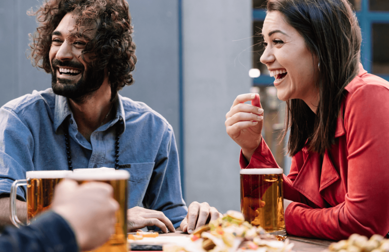 group of people sat together outside drinking and laughing