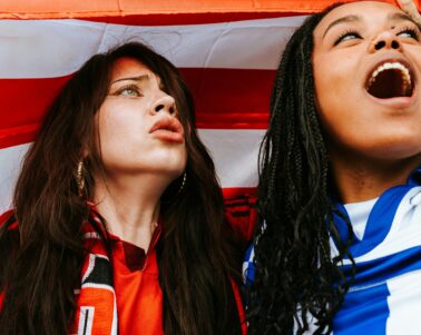 two people looking away from the camera reacting to the football